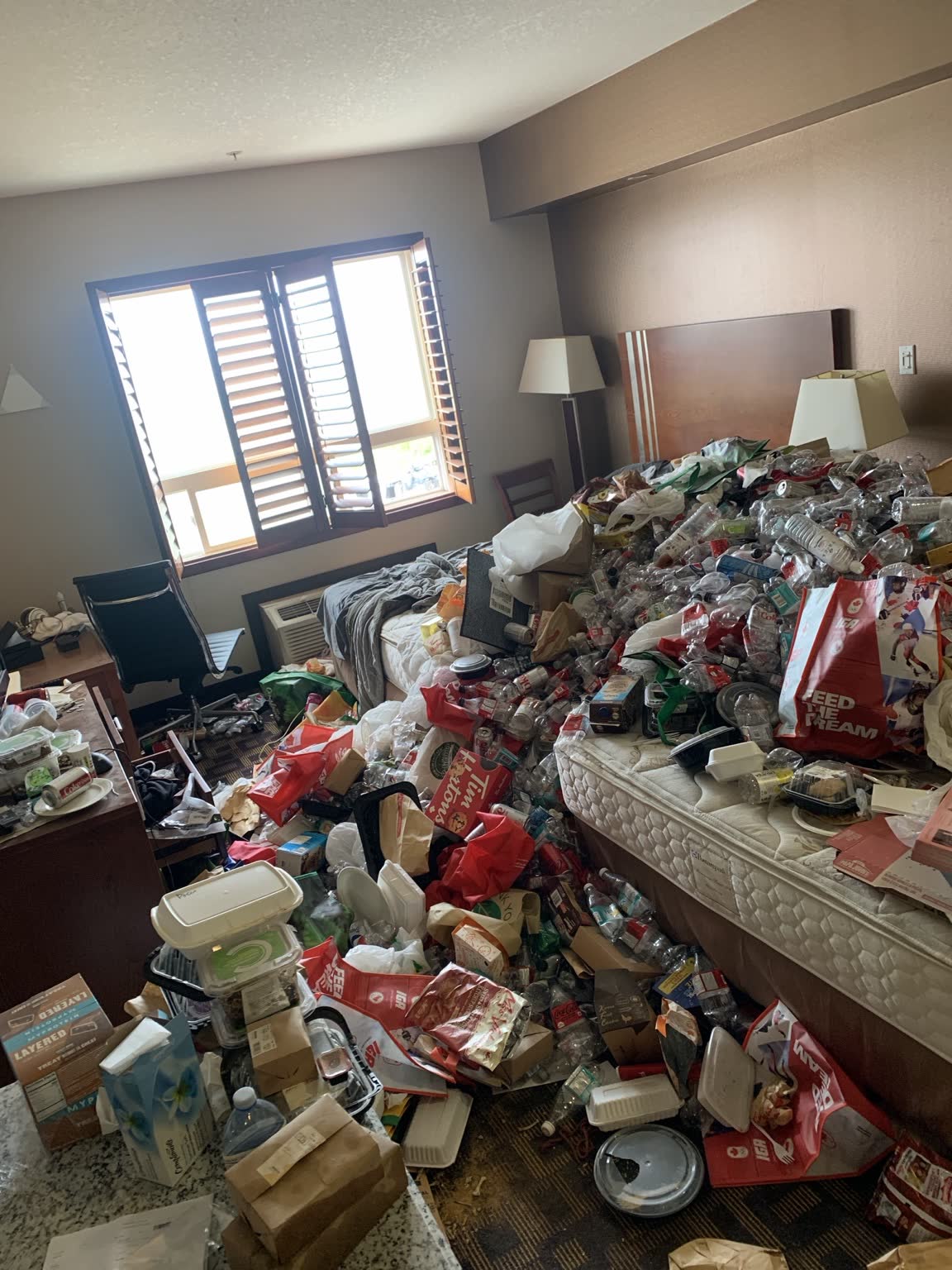 Heavily cluttered hotel room before cleanup
